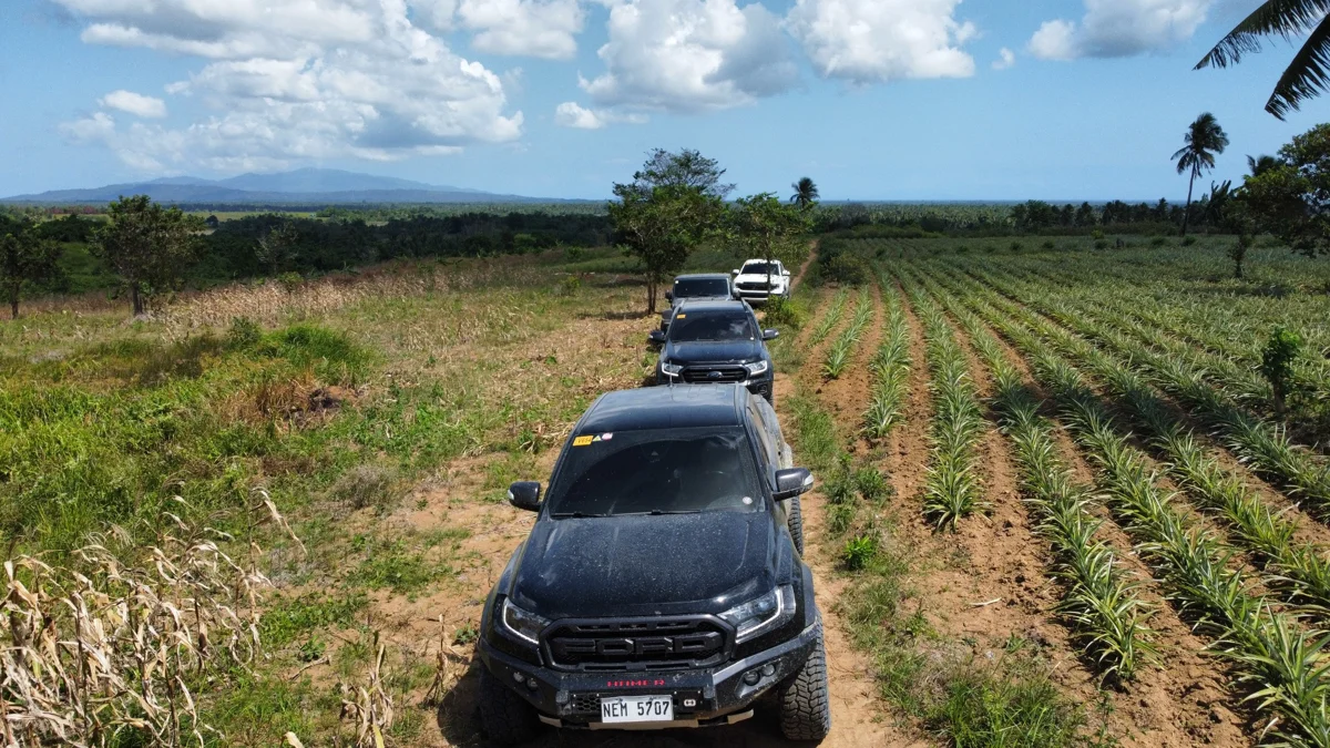 A convoy of 4x4 vehicles on a dirt trail in the Philippines, seen from above