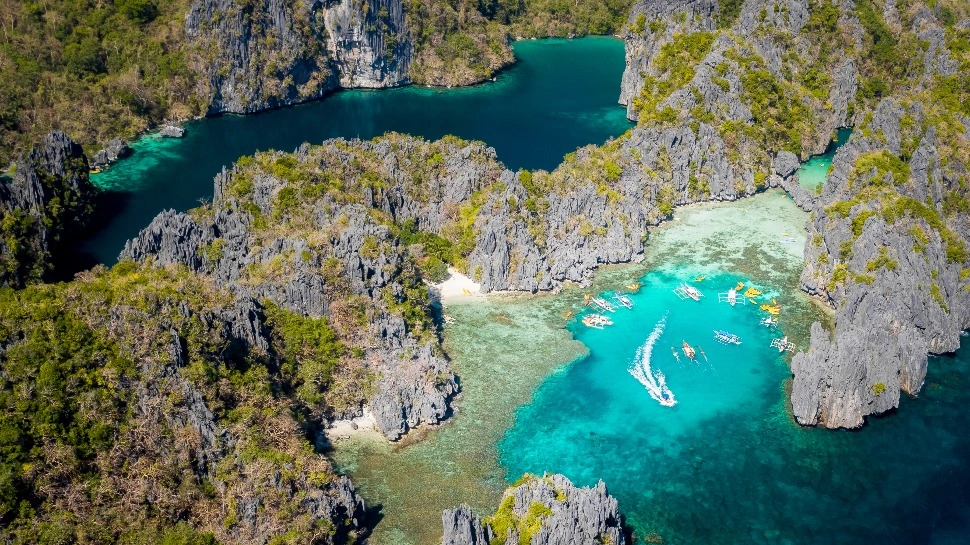 Outrigger boats moored in turquoise lagoons between limestone islands in Bacuit Bay, El Nido
