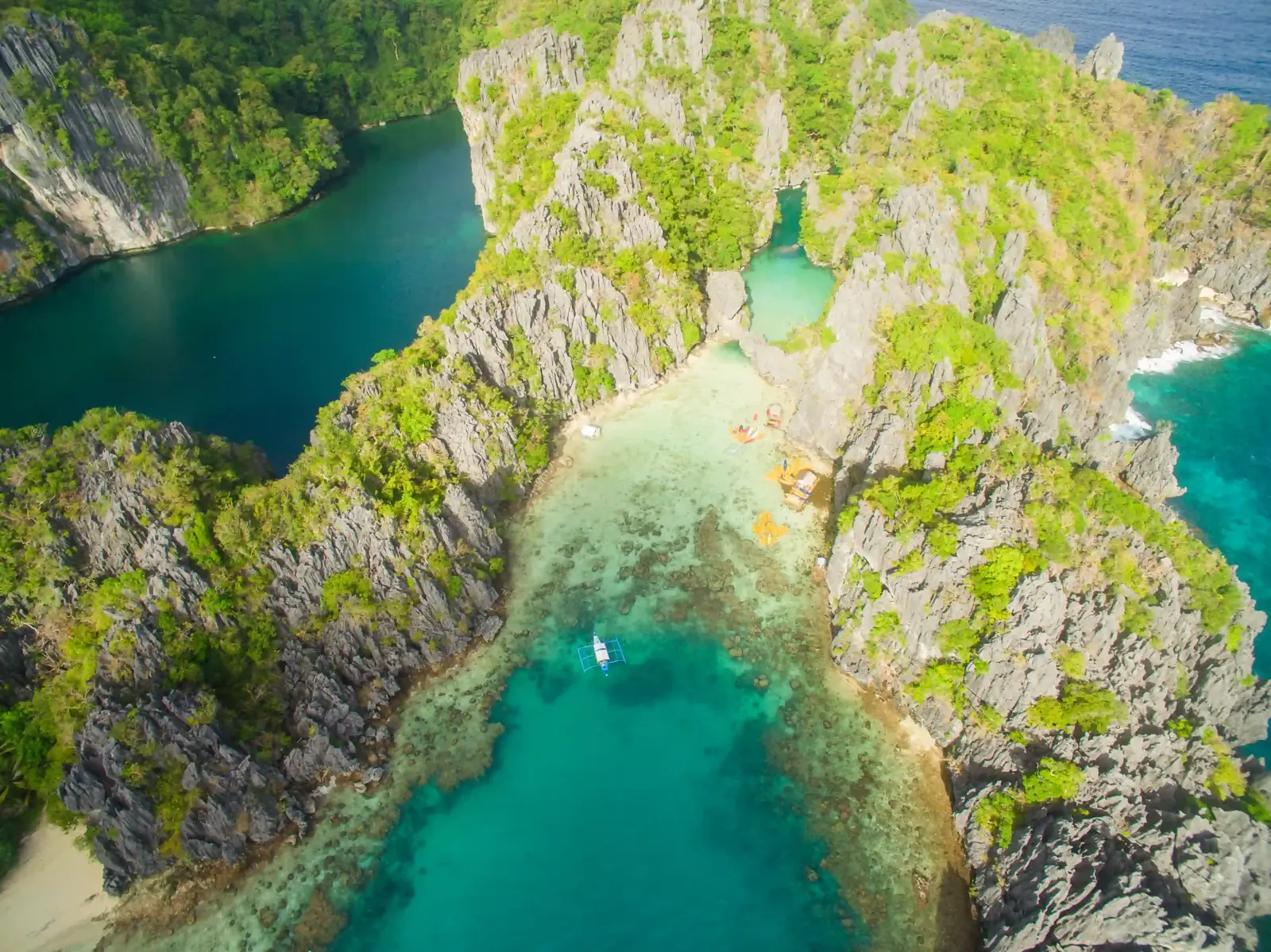 Outrigger boat floating over shallow reef at the mouth of a lagoon in El Nido, Palawan