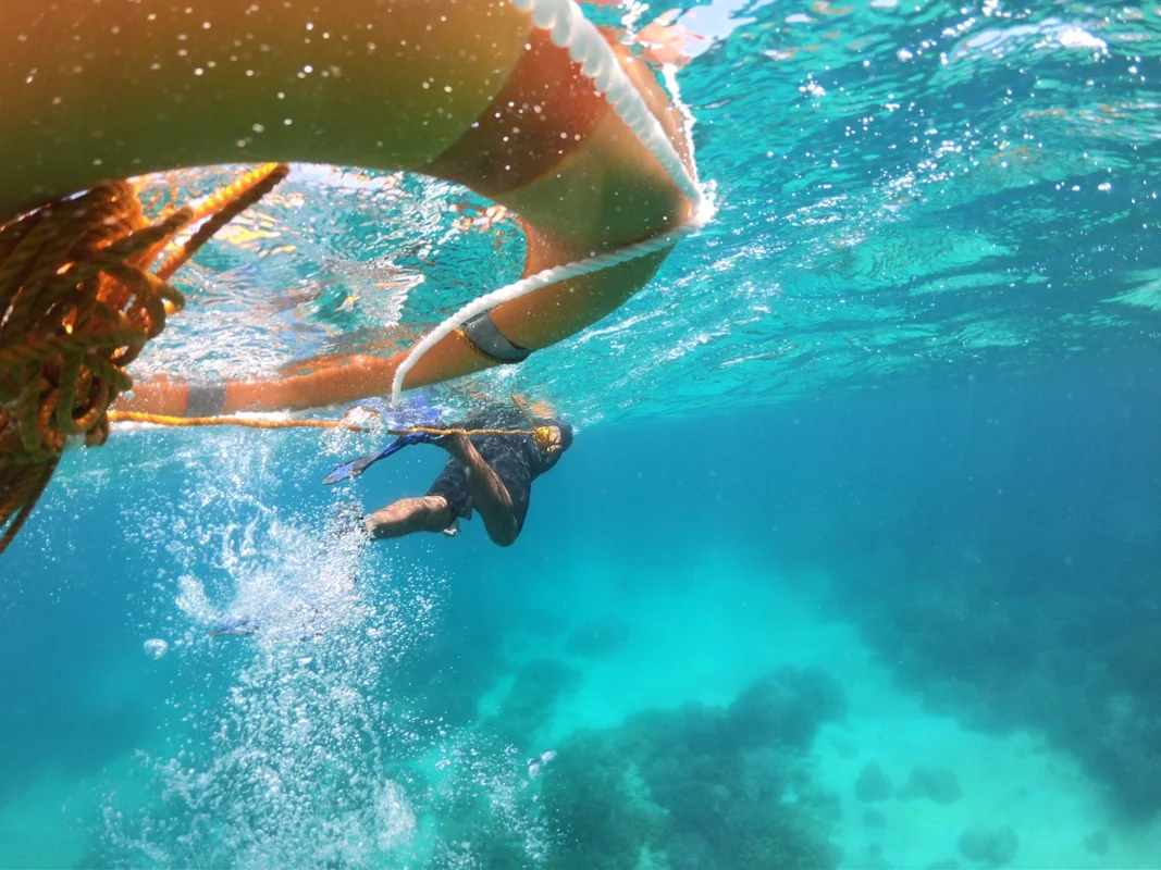 A freediver descending a line into deep blue water in the Philippines