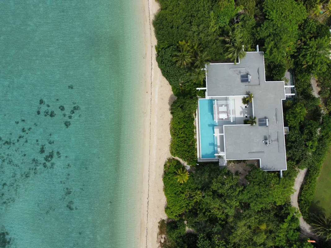 A luxury beachfront villa with a private pool above a turquoise bay