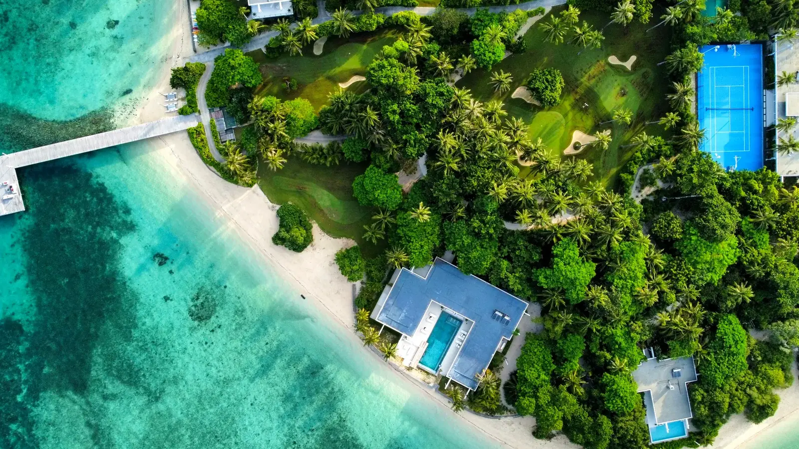 An island resort surrounded by clear shallow water and reef